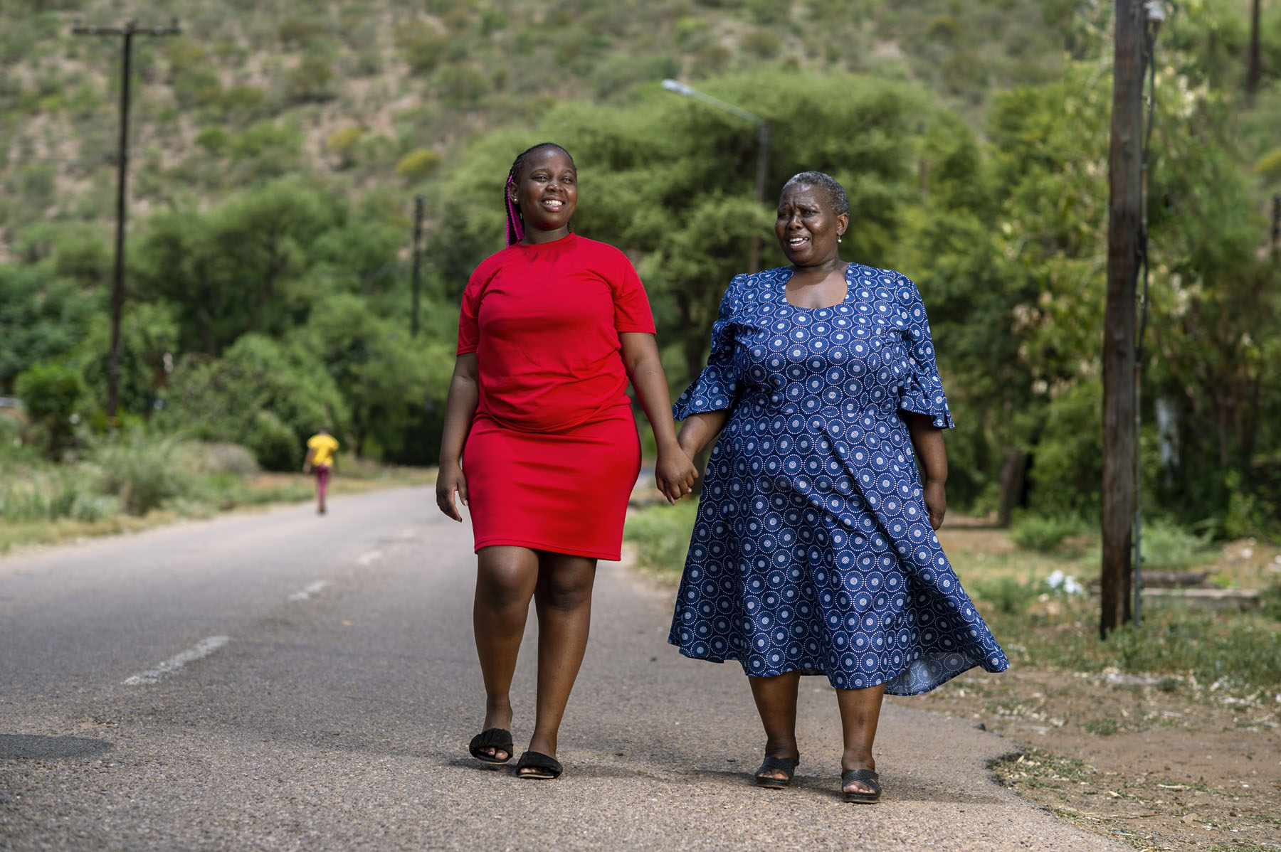 Kenielwe (in red) and her mother Cecilia (in Blue) walk around Lobatse town, in Botswana