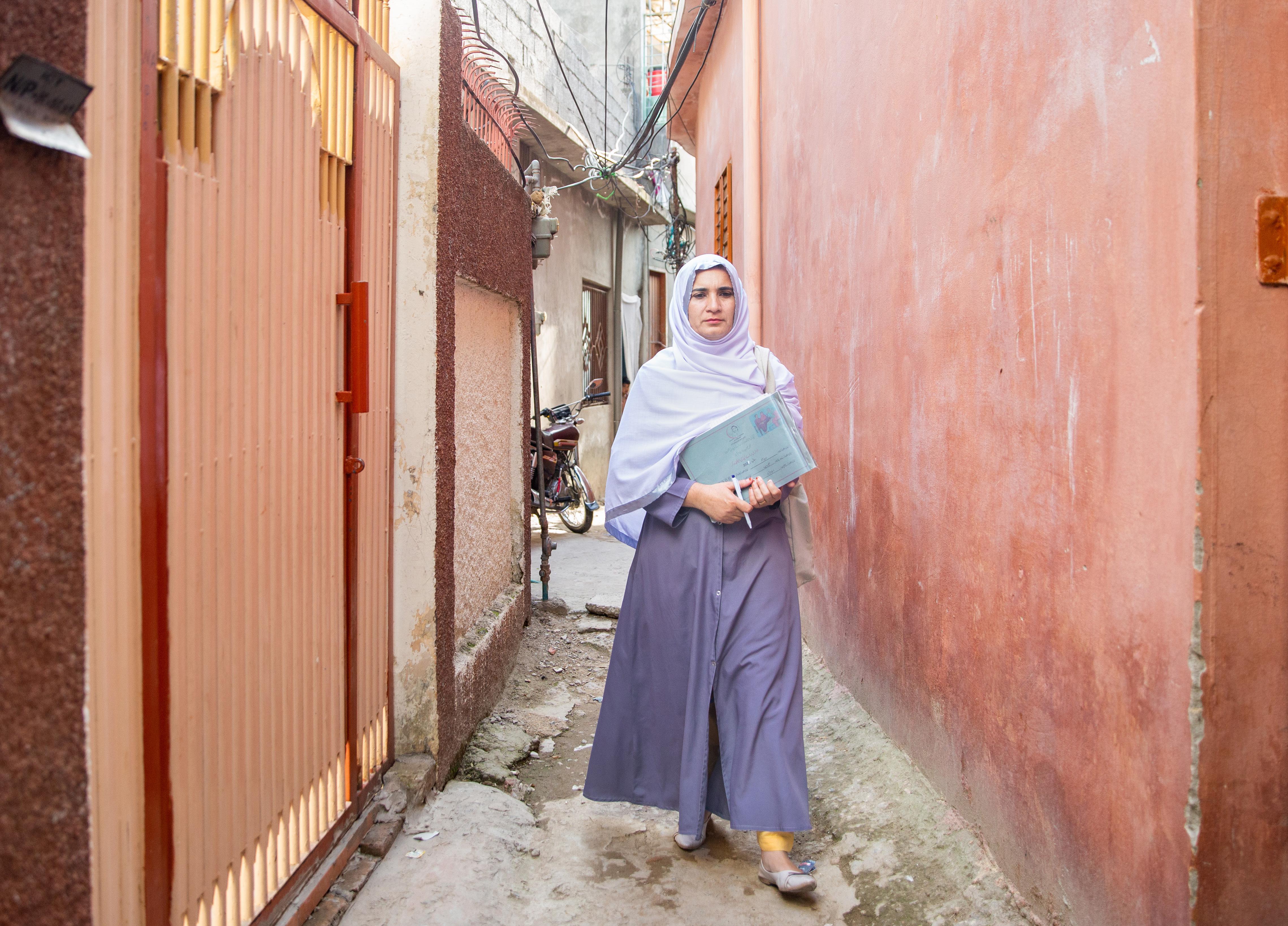 A health worker goes door-to-door to speak about health with girls and women, and to refer them to health clinics.