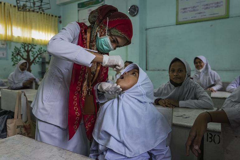 Polio campaign in Aceh A health care worker immunizing a female student in Aceh.