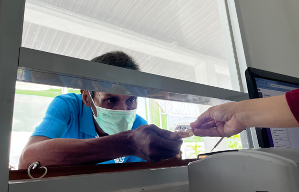 A man bends down at the drug counter to get his medicine.